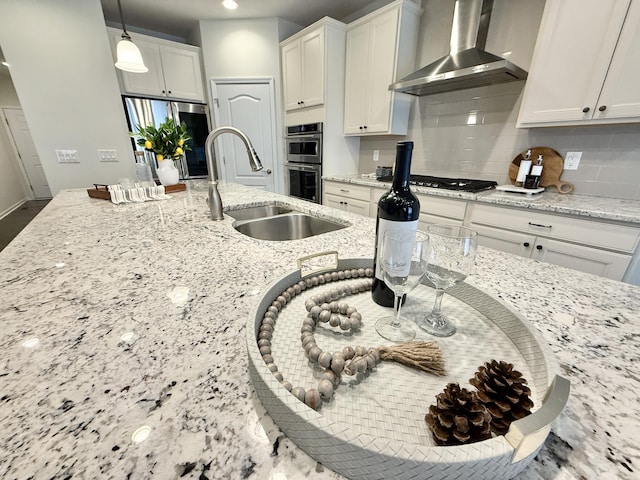 2763 Polson St, Ann Arbor, MI 48105 - kitchen featuring wall chimney range hood, a sink, appliances with stainless steel finishes, decorative backsplash, and light stone counters