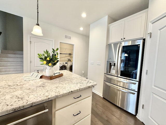 2763 Polson St, Ann Arbor, MI 48105 - kitchen with appliances with stainless steel finishes, separate washer and dryer, dark wood-type flooring, decorative light fixtures, and light stone counters