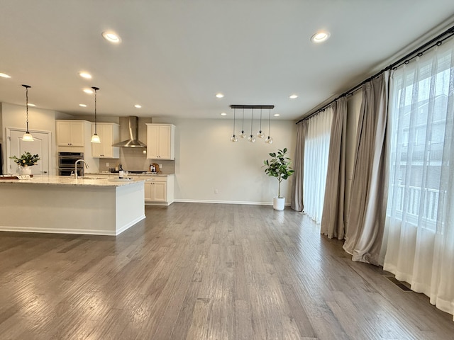 2763 Polson St, Ann Arbor, MI 48105 - kitchen featuring wall chimney range hood, white cabinets, dark wood-type flooring, recessed lighting, and light stone countertops
