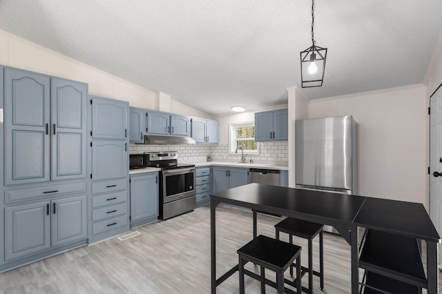2906 Frankfort Hwy, Frankfort, MI 49635 - kitchen with stainless steel appliances, a textured ceiling, blue cabinetry, backsplash, and light wood finished floors