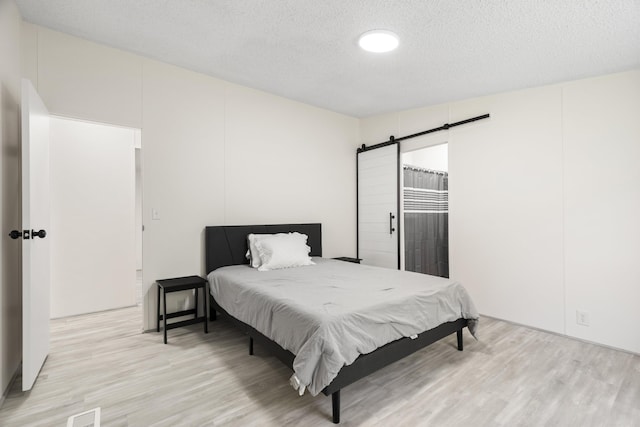 2906 Frankfort Hwy, Frankfort, MI 49635 - bedroom featuring a barn door, light wood-style floors, and a textured ceiling