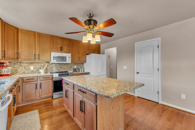 25340 Villagewood, South Lyon, MI 48178 - kitchen with white appliances, light wood-style floors, backsplash, ceiling fan, and light stone countertops