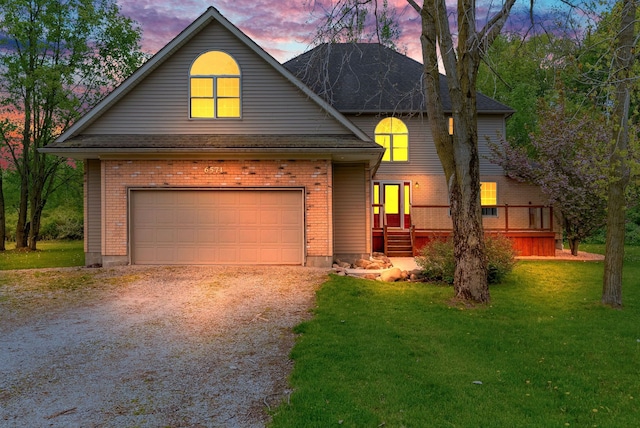 traditional-style house featuring driveway, a lawn, an attached garage, and brick siding
