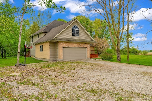 view of side of home with driveway, a lawn, brick siding, and an attached garage