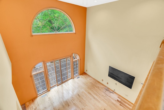unfurnished living room featuring wood finished floors and a high ceiling
