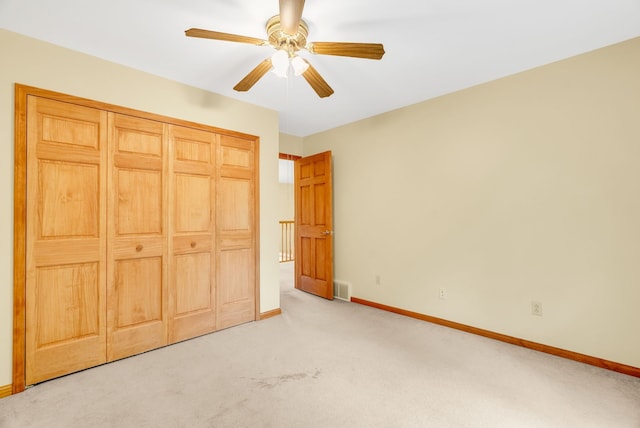 unfurnished bedroom with light colored carpet, baseboards, a closet, and a ceiling fan
