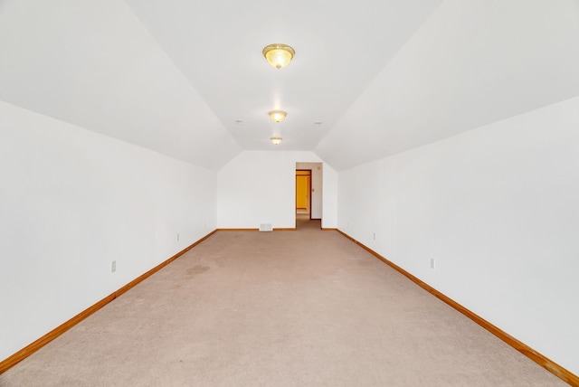 bonus room featuring baseboards, vaulted ceiling, and light colored carpet