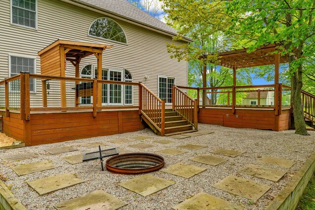 back of property with a fire pit, a wooden deck, a patio, stairs, and a shingled roof