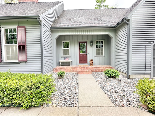 4909 Barnstable Ln, Lansing, MI 48906 - view of exterior entry featuring roof with shingles, a porch, board and batten siding, and a chimney