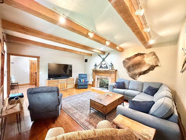 4909 Barnstable Ln, Lansing, MI 48906 - living room featuring rail lighting, light wood-style flooring, beam ceiling, and a fireplace