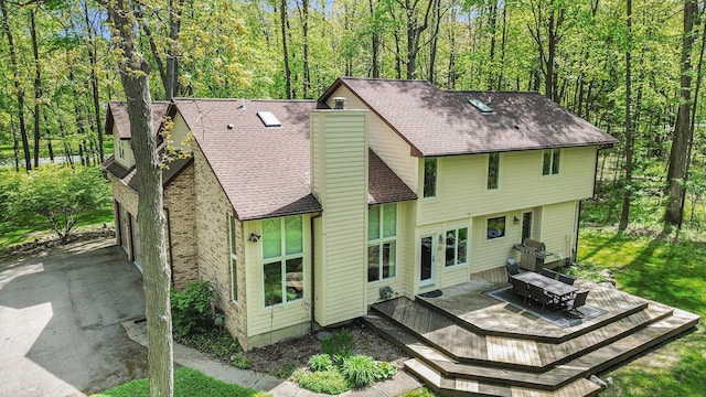 8461 Webster Hills Rd, Dexter, MI 48130 - back of property featuring a chimney, roof with shingles, a deck, and a view of trees