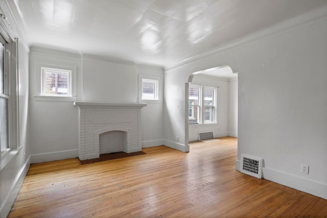8916 Mendota St, Detroit, MI 48204 - unfurnished living room featuring arched walkways, light wood-type flooring, baseboards, a fireplace, and crown molding