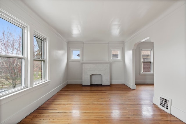 8916 Mendota St, Detroit, MI 48204 - unfurnished living room featuring a brick fireplace, light wood-style floors, baseboards, and arched walkways