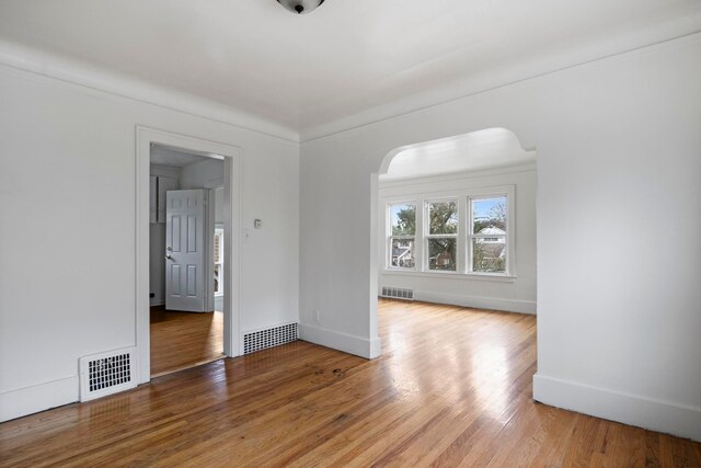 8916 Mendota St, Detroit, MI 48204 - empty room with arched walkways, light wood-style flooring, and baseboards