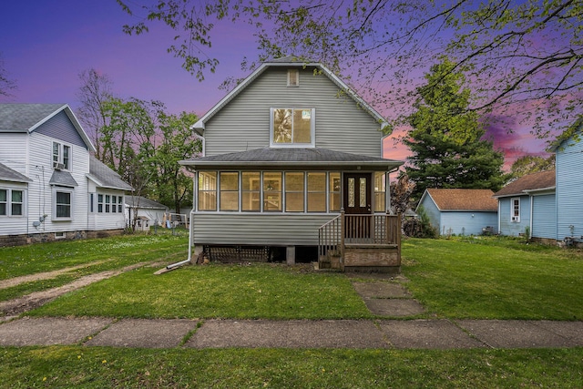 214 S Monroe St, Sturgis, MI 49091 - back of house at dusk featuring a lawn and a sunroom