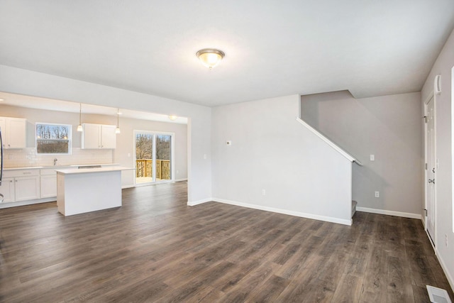 7987 Sierra Dr, Belding, MI 48809 - unfurnished living room featuring baseboards, dark wood-type flooring, a sink, and stairs