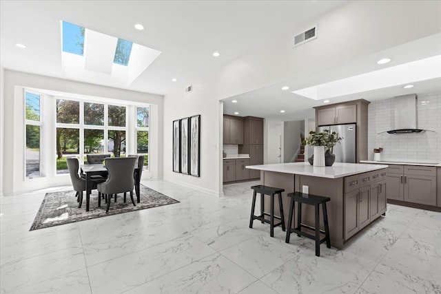 49712 Geddes Rd, Canton, MI 48188 - kitchen featuring freestanding refrigerator, wall chimney exhaust hood, a skylight, a towering ceiling, and light marble finish flooring