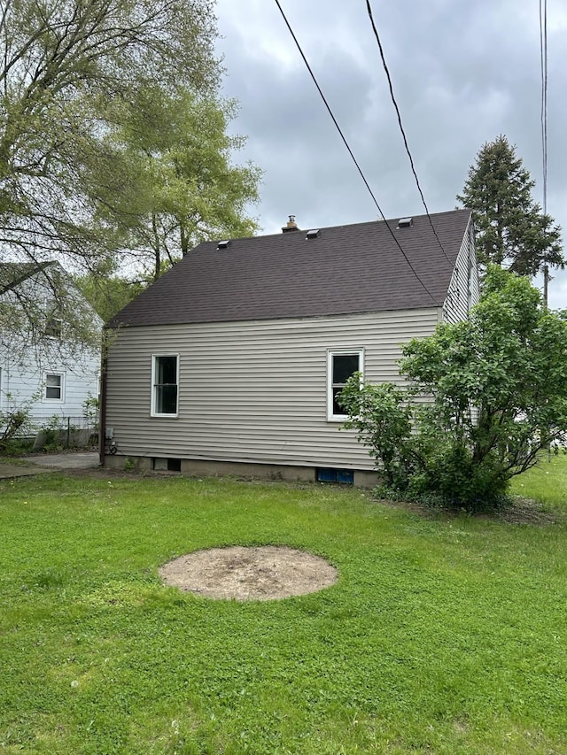 back of house with roof with shingles and a lawn