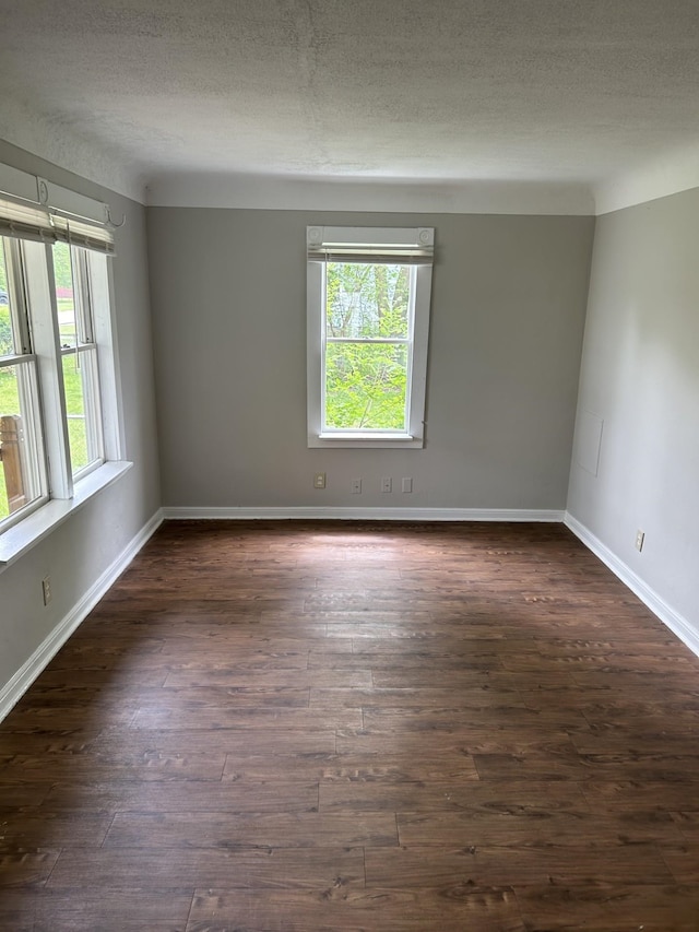 empty room with dark wood finished floors, baseboards, and a textured ceiling