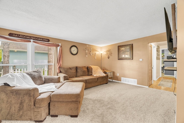 living room with a textured ceiling, carpet floors, and baseboards