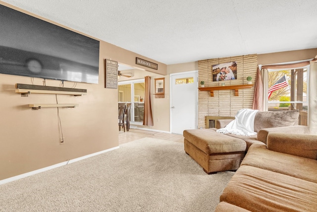 carpeted living area featuring ceiling fan, a textured ceiling, a brick fireplace, and baseboards
