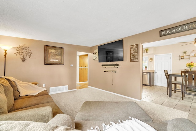 living room with baseboards, light tile patterned floors, light colored carpet, and ceiling fan