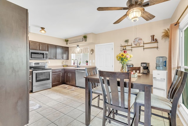 kitchen featuring stainless steel appliances, light countertops, plenty of natural light, and dark brown cabinets