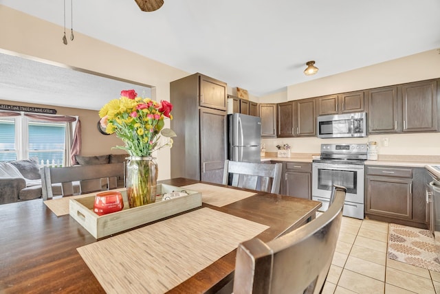 kitchen with stainless steel appliances, light countertops, light tile patterned floors, and dark brown cabinets