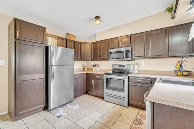 kitchen featuring stainless steel appliances, a sink, light countertops, and light tile patterned floors