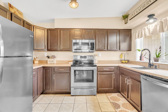 kitchen featuring appliances with stainless steel finishes, a sink, light countertops, and light tile patterned flooring