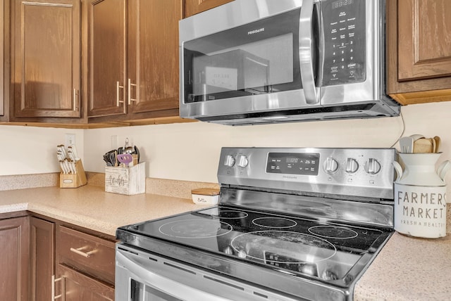 kitchen featuring appliances with stainless steel finishes, light countertops, and brown cabinetry