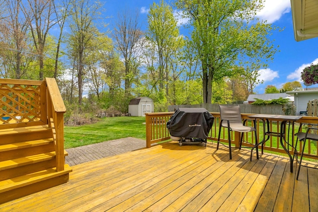 wooden deck with a shed, an outbuilding, and a grill