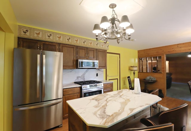 6452 Brian Circle Ln, Burton, MI 48509 - kitchen with appliances with stainless steel finishes, wood walls, a chandelier, a kitchen island, and backsplash