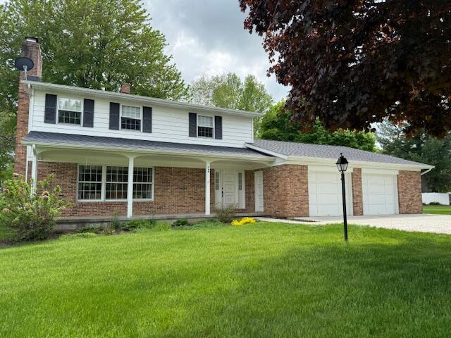 200 Brink St, Grant, MI 49327 - traditional home featuring a garage, a chimney, driveway, a front lawn, and brick siding