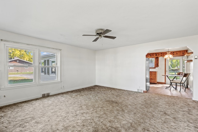 434 Walnut St, Howard City, MI 49329 - unfurnished room featuring carpet flooring, baseboards, a ceiling fan, arched walkways, and a chandelier