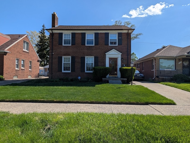 9864 E Outer Dr, Detroit, MI 48224 - colonial house with a chimney, a front lawn, and brick siding