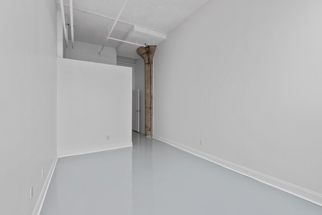 spare room featuring finished concrete flooring and baseboards