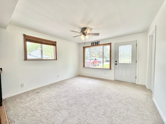 spare room featuring healthy amount of natural light, a ceiling fan, a textured ceiling, and carpet flooring