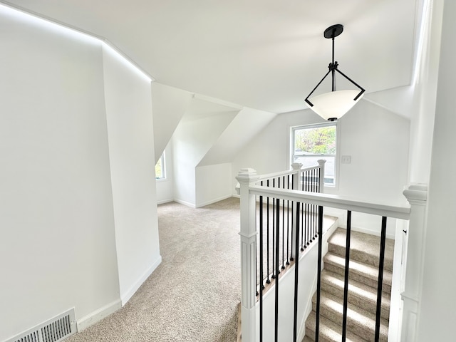 hall featuring carpet floors, an upstairs landing, baseboards, and vaulted ceiling