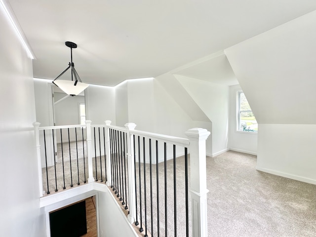 hallway featuring an upstairs landing, carpet flooring, and baseboards