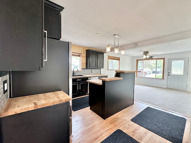 kitchen with dark cabinetry, butcher block counters, a sink, and ceiling fan