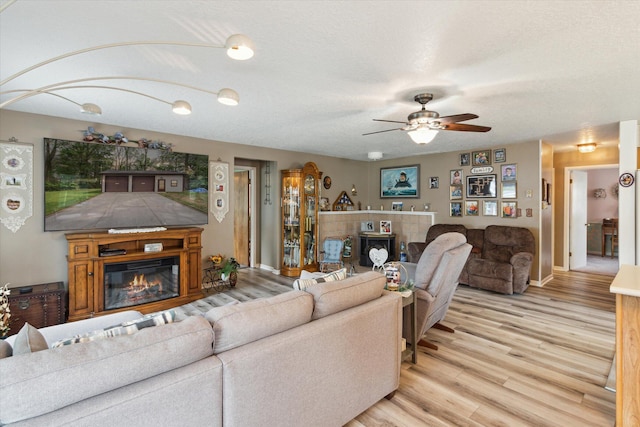 204 Crockett Dr, Quincy, MI 49082 - living area featuring a glass covered fireplace, a ceiling fan, and light wood-type flooring