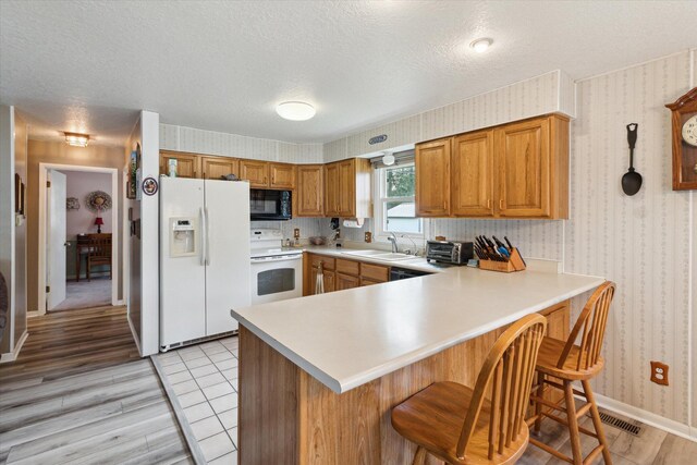 204 Crockett Dr, Quincy, MI 49082 - kitchen with black appliances, wallpapered walls, light countertops, a peninsula, and a textured ceiling