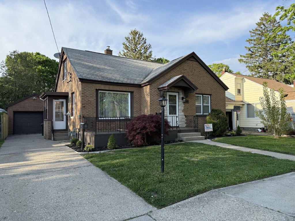 1060 Ireland Ave, Muskegon, MI 49441 - view of front facade featuring an outbuilding, brick siding, concrete driveway, a chimney, and roof with shingles