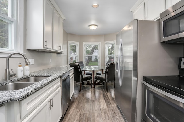 kitchen with stainless steel appliances, a sink, dark wood finished floors, white cabinetry, and light stone counters