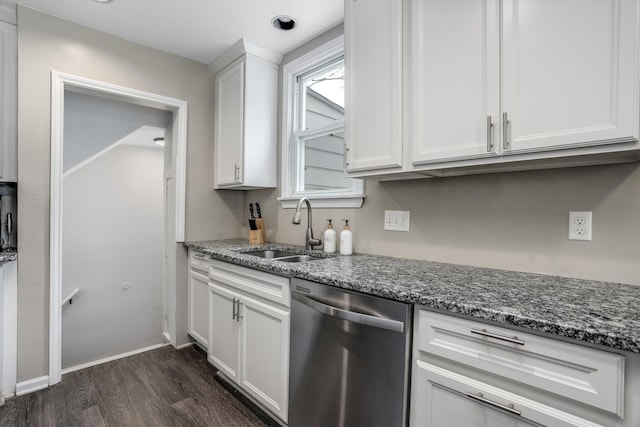 kitchen with stainless steel dishwasher, a sink, dark wood-type flooring, white cabinetry, and dark stone counters