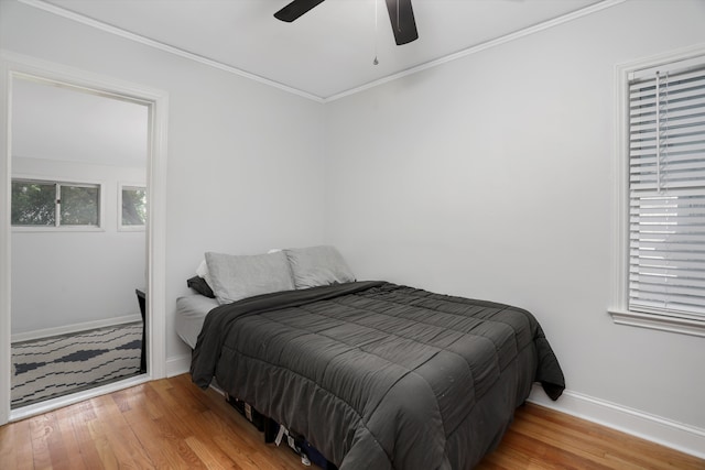 bedroom with wood finished floors, baseboards, ornamental molding, and ceiling fan