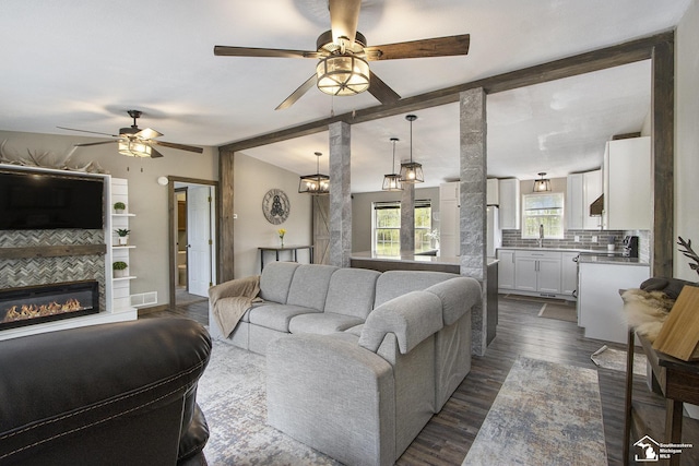 635 Pokey Dr, Hastings, MI 49058 - living area with ceiling fan, beamed ceiling, dark wood-style flooring, and a glass covered fireplace