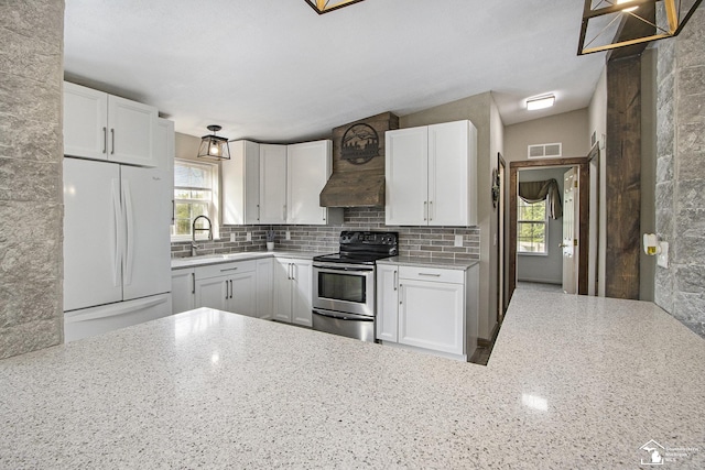 635 Pokey Dr, Hastings, MI 49058 - kitchen with stainless steel electric range, freestanding refrigerator, light stone counters, backsplash, and white cabinets