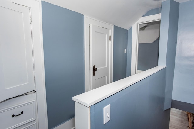 corridor featuring lofted ceiling and wood finished floors